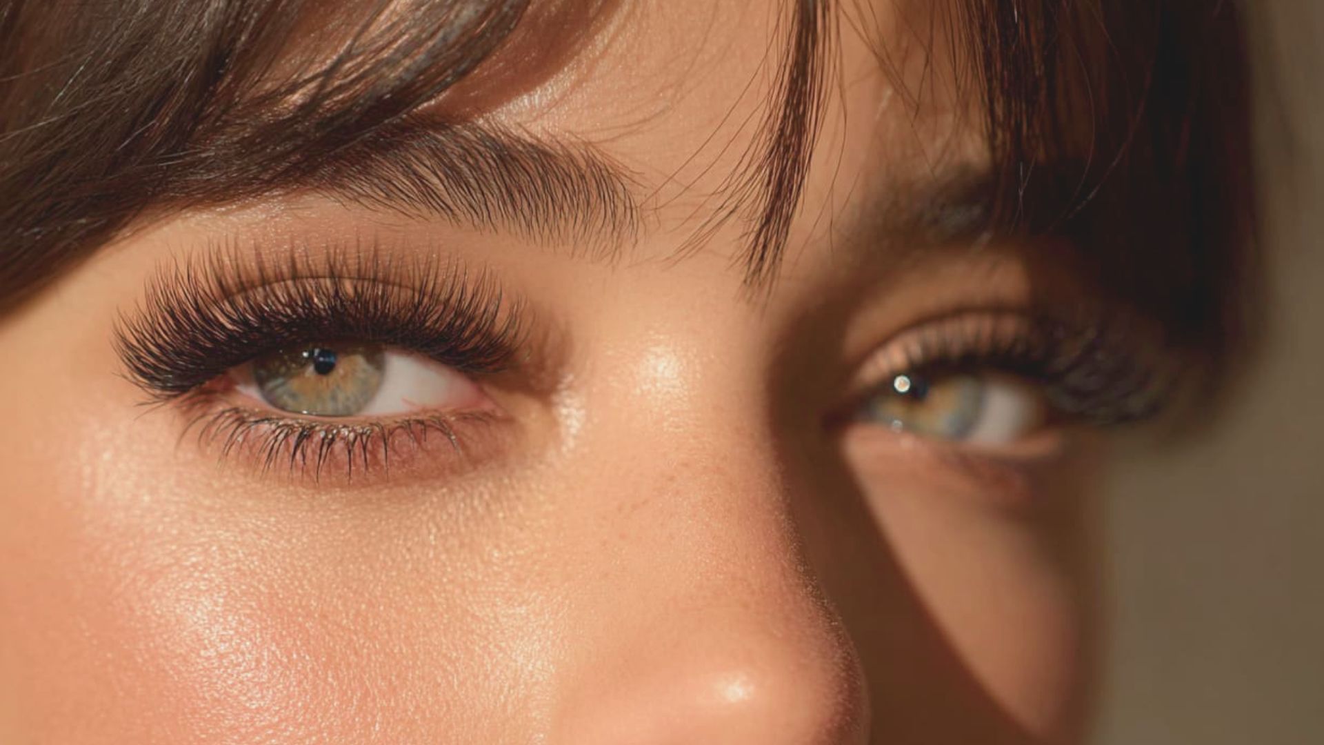 Close-up of a woman's eyes showcasing long, elegant lashes against a soft, blurred background.