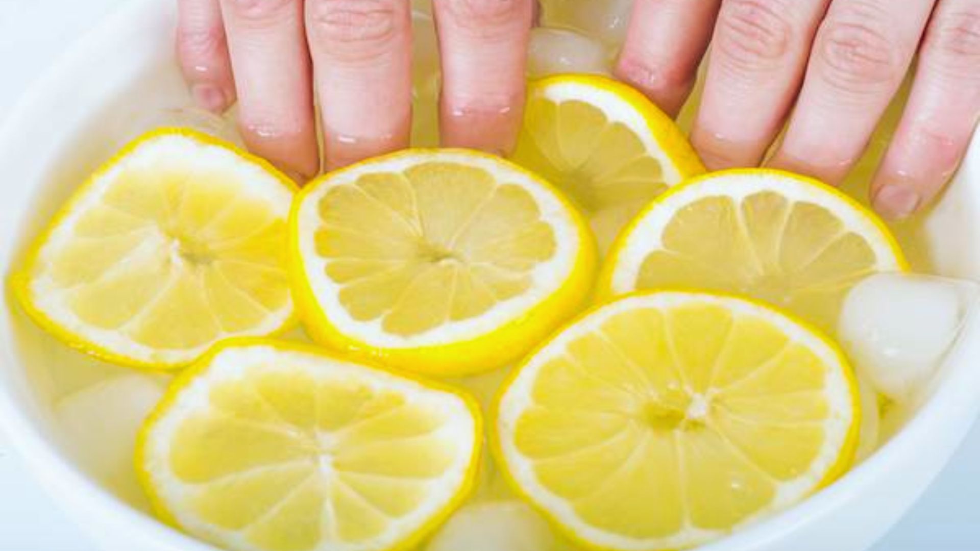 A person's hands hold a bowl filled with fresh lemon slices, showcasing their vibrant yellow color and textured skin.