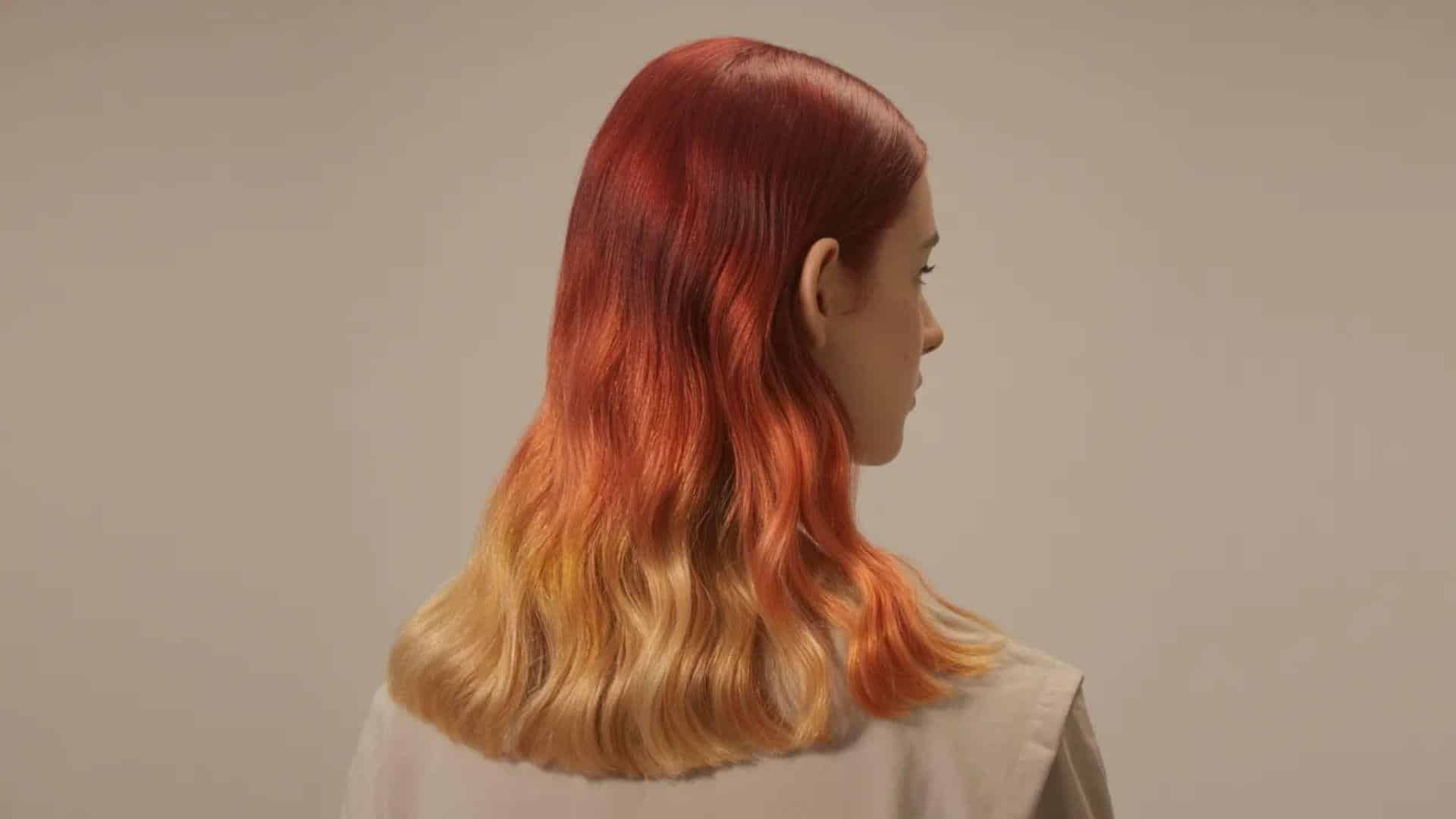 A woman with vibrant red hair and striking blonde hair stands together, showcasing a unique hairstyle combination.