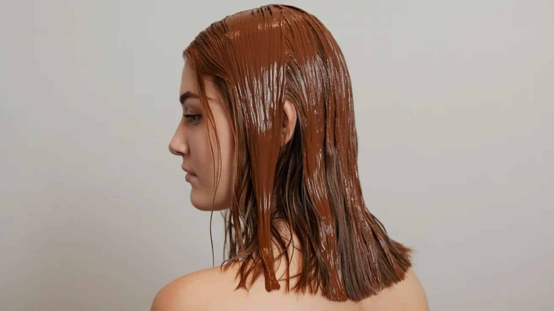 A woman with chocolate smeared in her hair, smiling playfully at the camera.