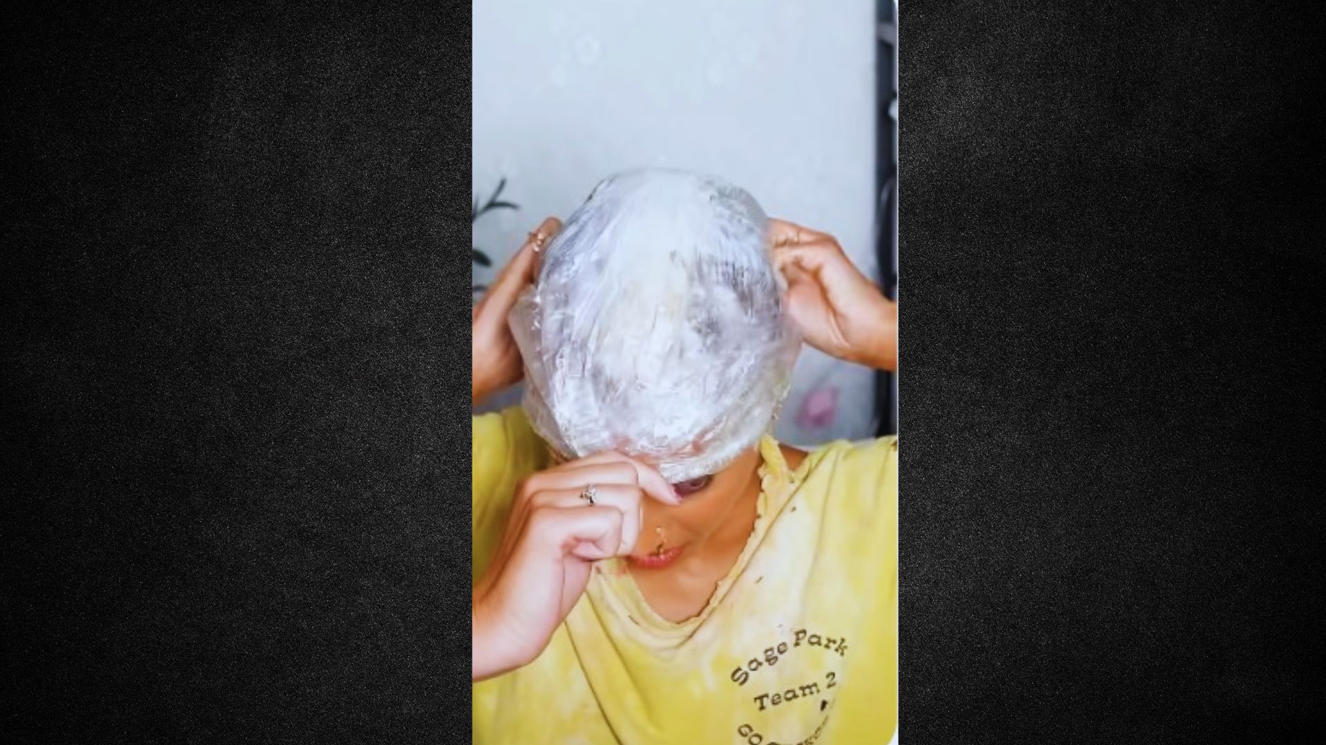 A woman is securing her hair inside a clear plastic bag for storage or protection.