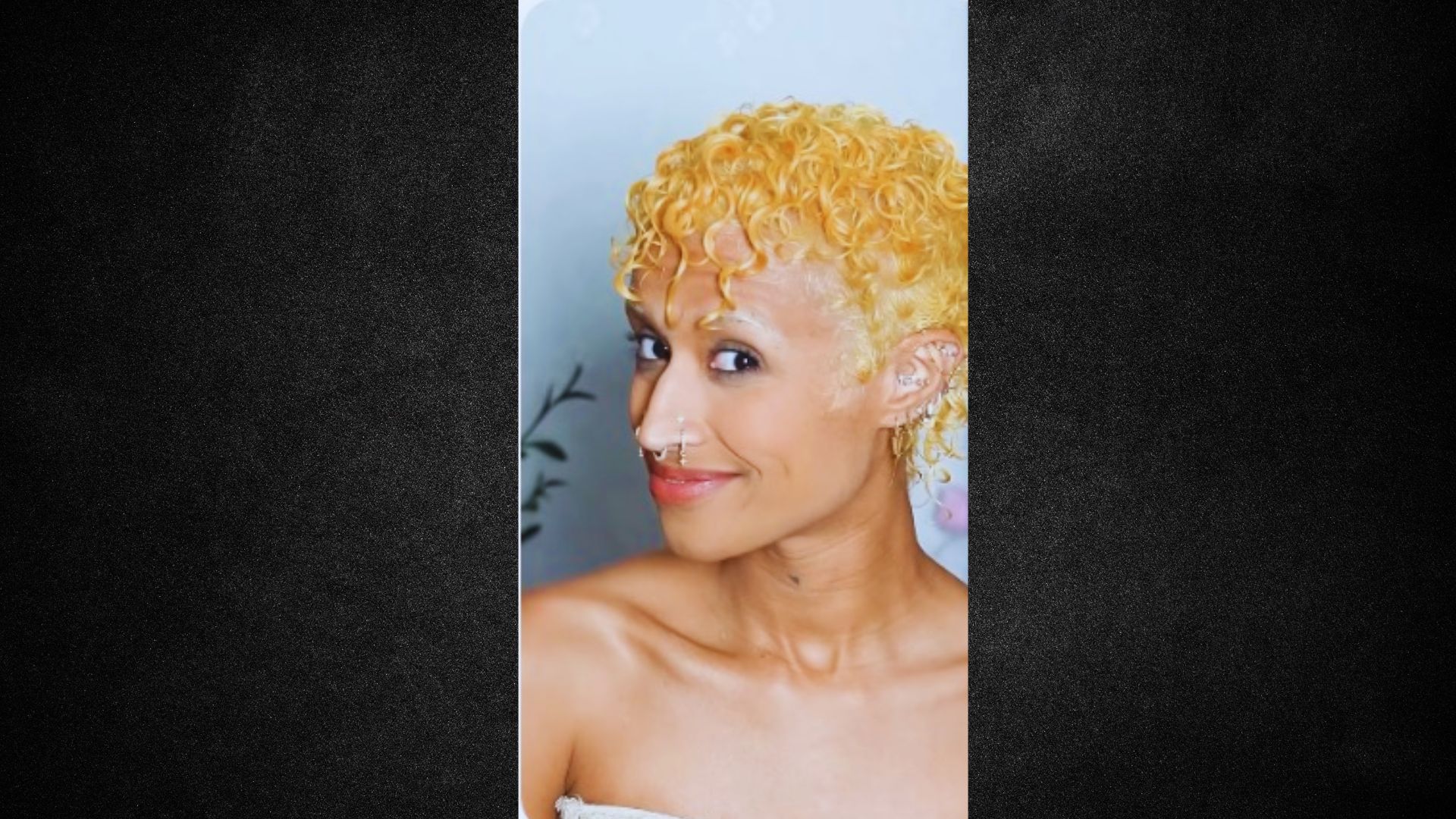 A woman with yellow hair is smiling warmly at the camera, exuding a cheerful and friendly demeanor.