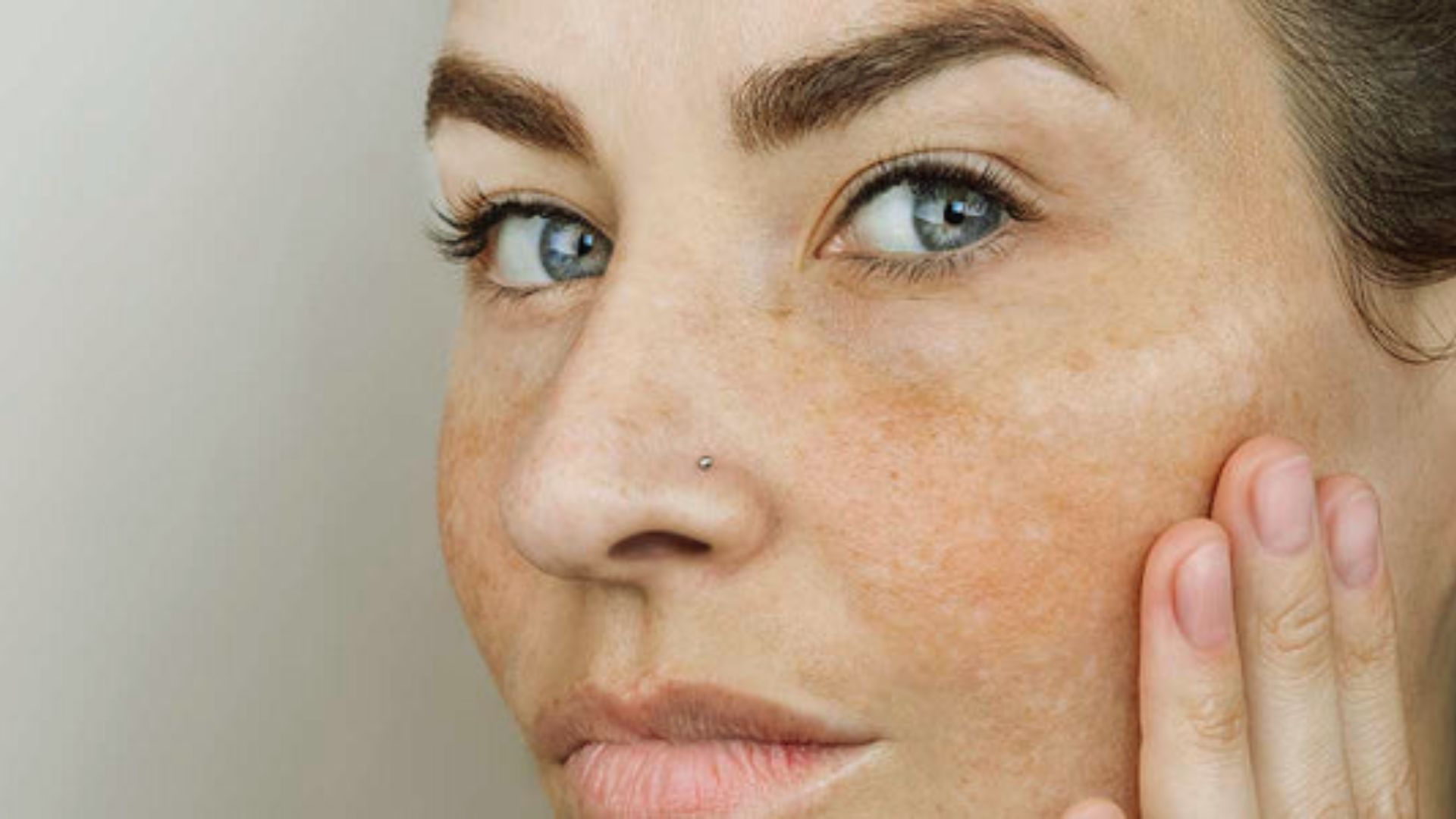 A close-up of a woman’s face reveals her freckles, highlighting her unique features and cheerful demeanor.
