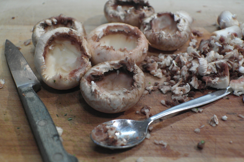 Remove the mushroom stalks. Using the tip of a sharp knife score the mushroom and then scoop out the mushroom 'flesh' with a spoon. Be careful not to scoop out too much - you don't want to break the bottom of the mushroom (otherwise the filling will leak out!)