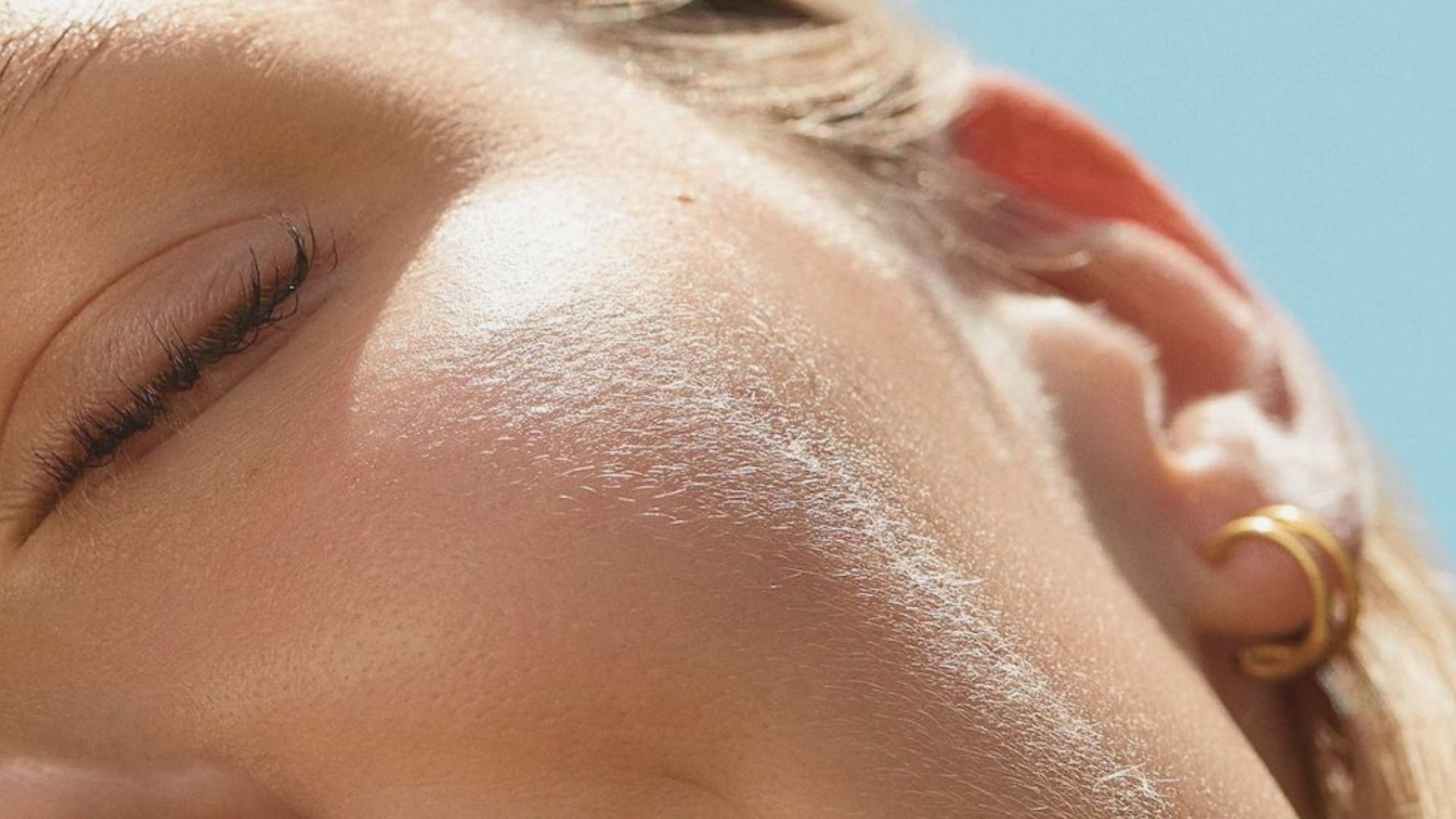 A woman with closed eyes wearing a gold hoop earring, conveying a serene and contemplative expression.