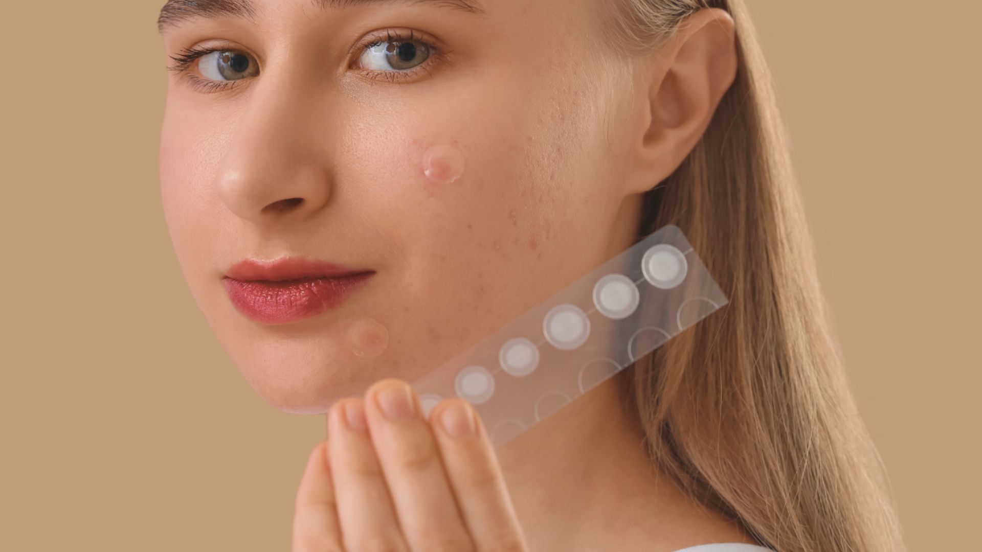 A woman holds a plastic piece with a white sticker, showcasing a pimple patch for skincare use.