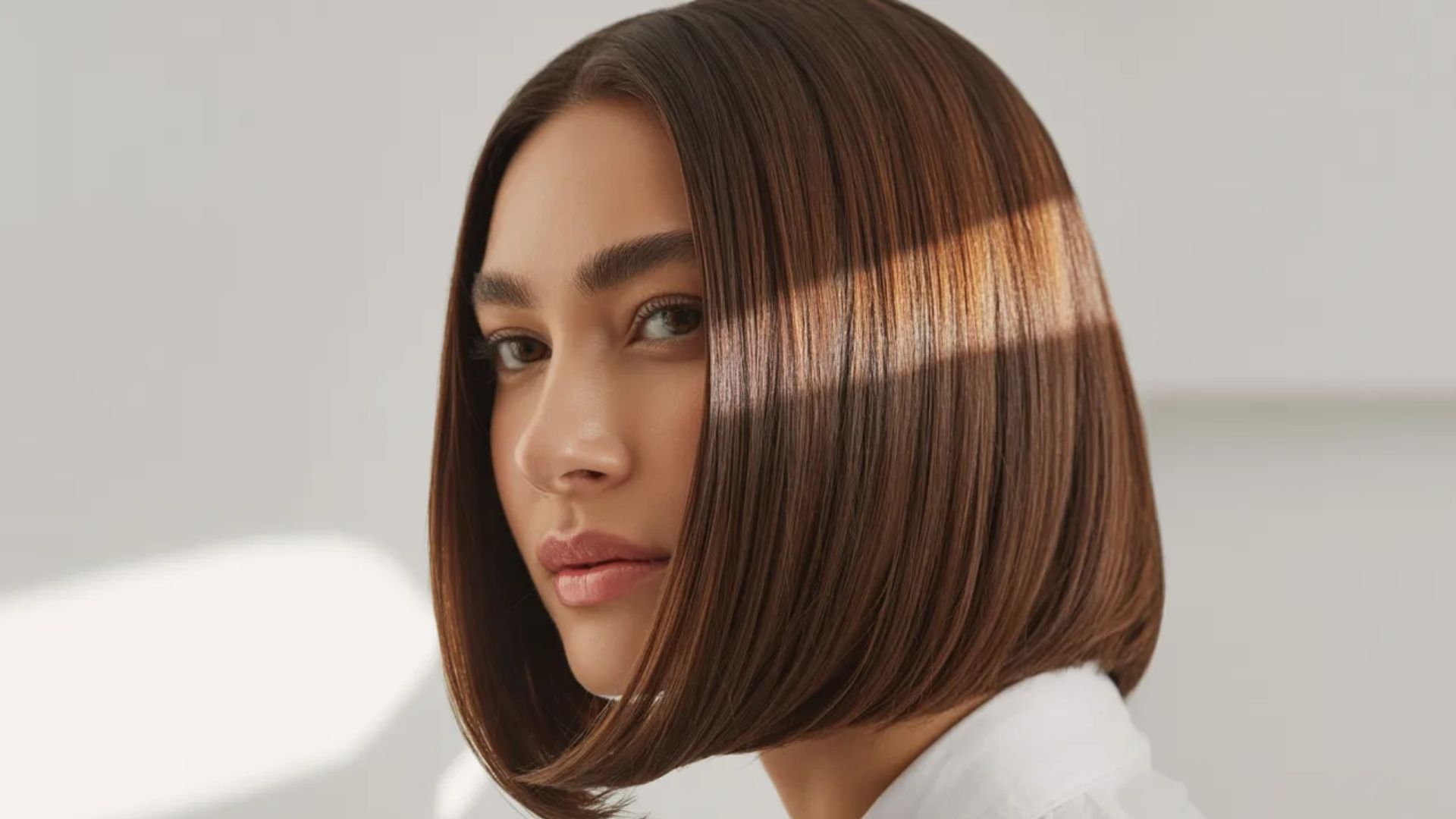 A woman with a bob haircut gazes thoughtfully to the side, her expression contemplative.