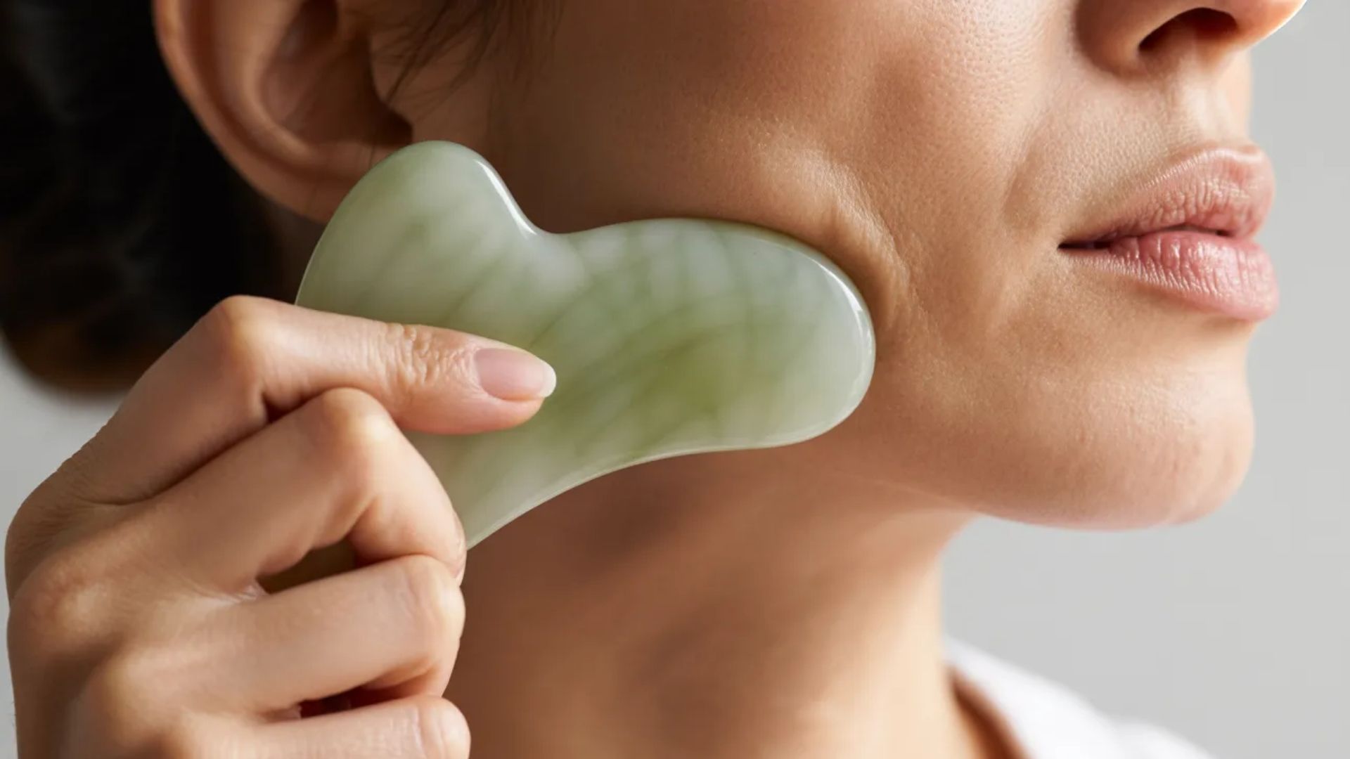 6. A woman holds a smooth green jade stone in her hand, showcasing its vibrant color and natural texture.