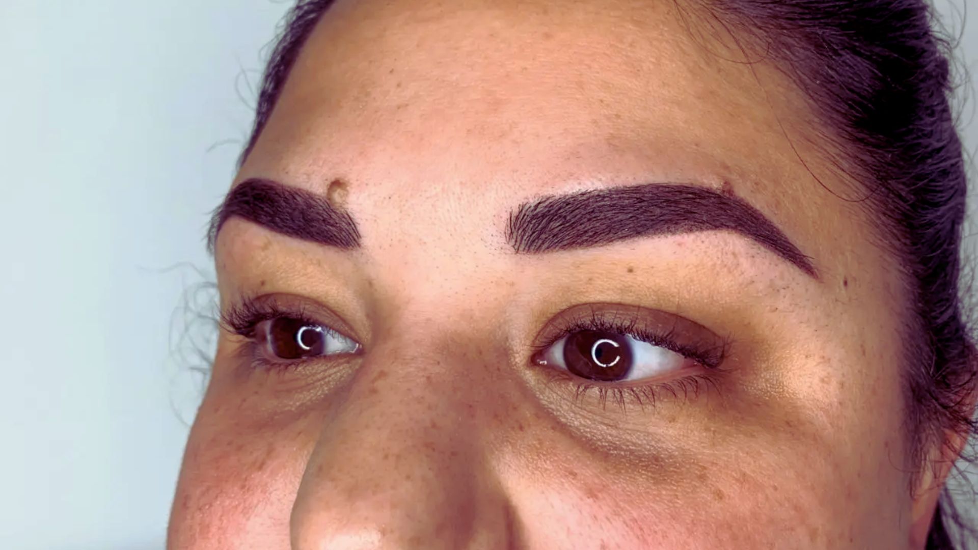 A woman with brown eyes and brown eyebrows gazes thoughtfully at the camera.