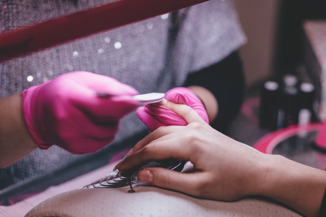 A woman receiving a manicure in a bright, modern nail salon, surrounded by nail polish and beauty tools.