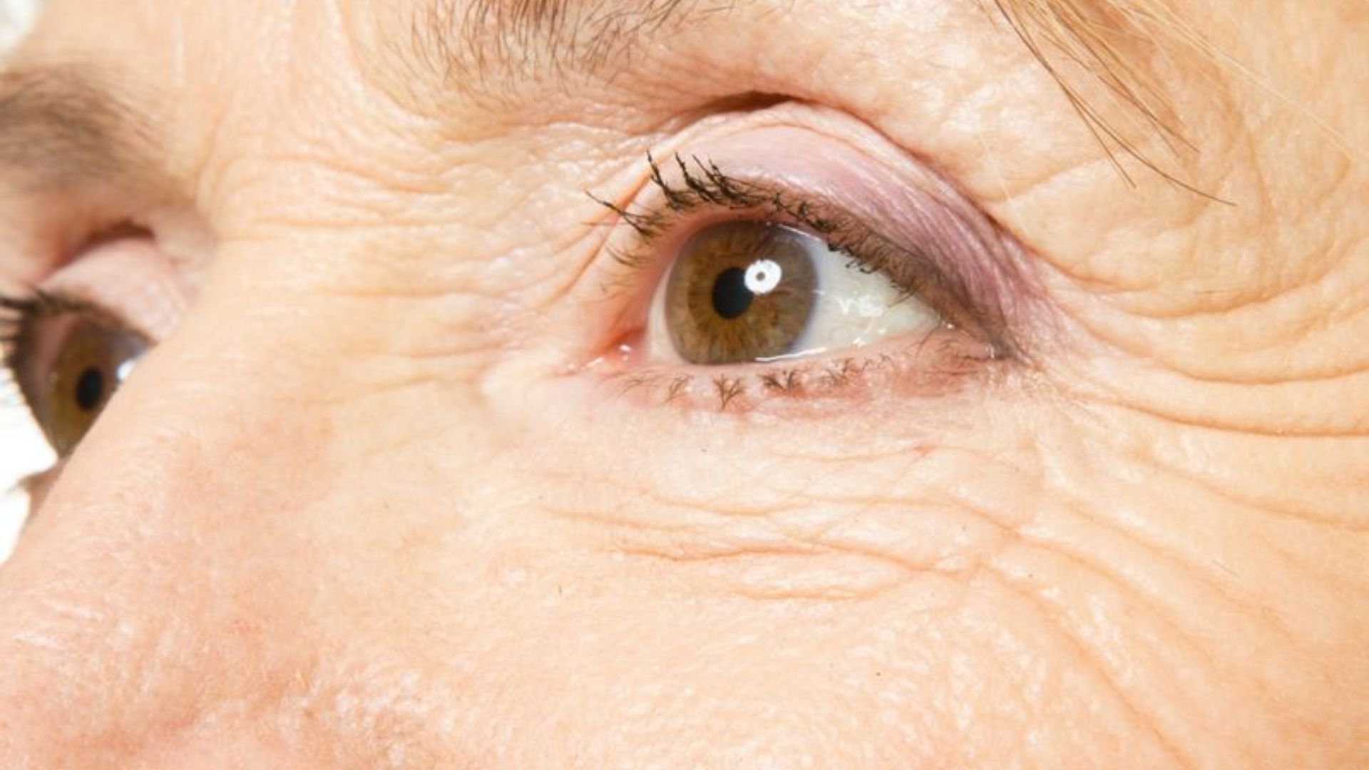 Close-up of an older woman's eye, showcasing fine lines and a thoughtful expression.