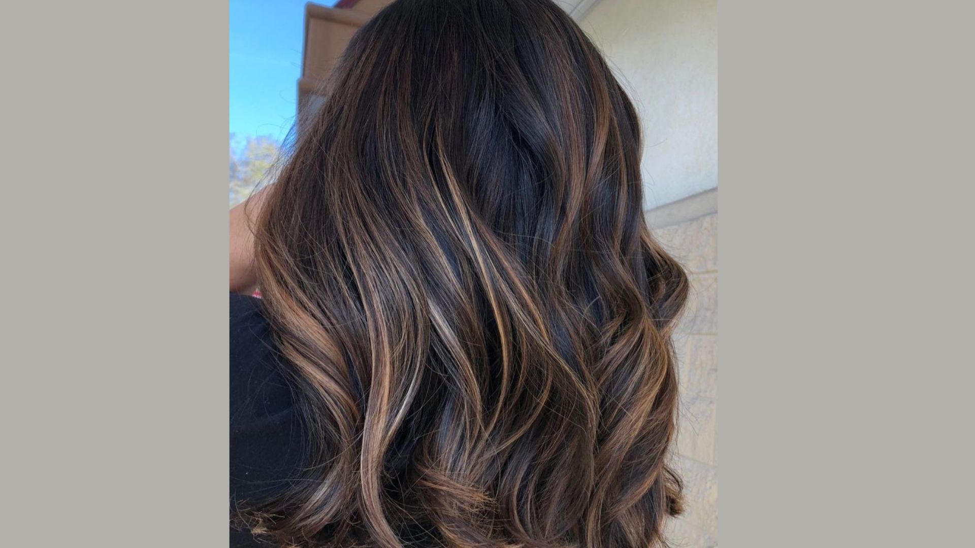 The back of a woman's head showcasing long, dark hair cascading down her shoulders.