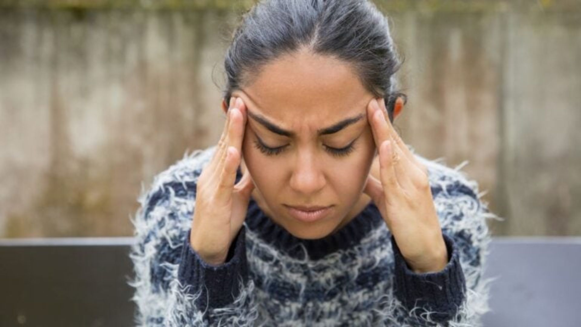 A woman holds her head in pain, illustrating the challenges of the "In-Between" phase during the Die-Off Effect.