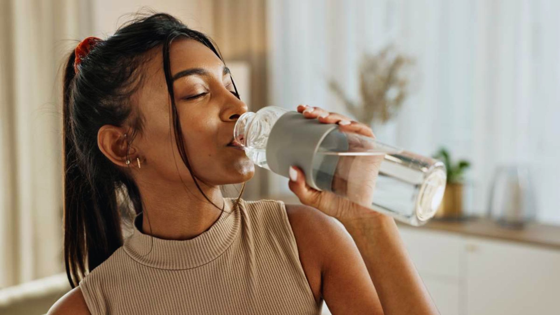 A woman takes a sip from a water bottle, staying hydrated during her activity.