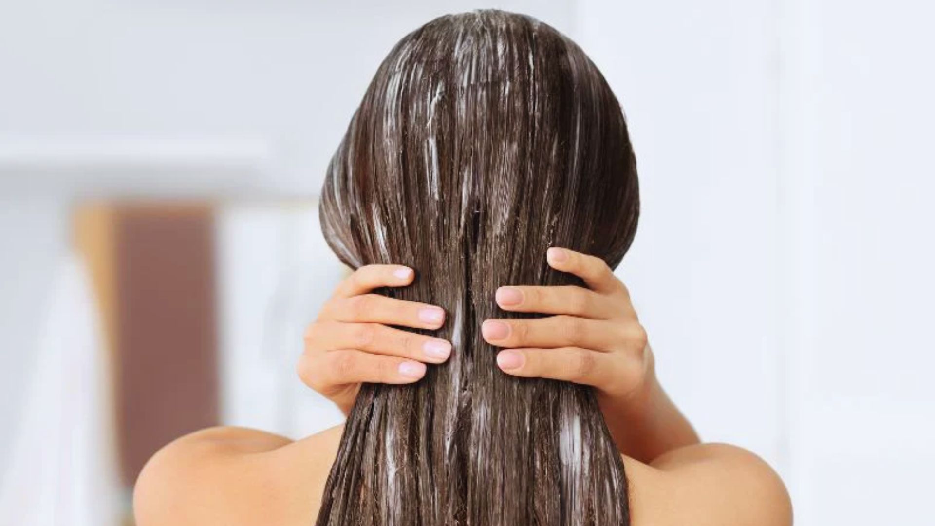 A woman holds her hair up to her head, preparing to style or secure it in place.