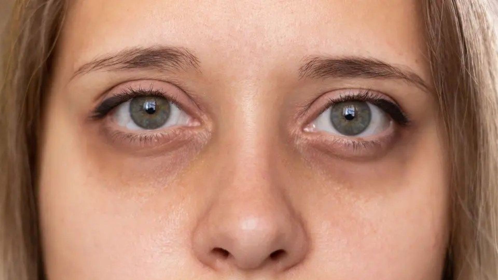 Detailed close-up of a woman's face, focusing on her striking green eye, emphasizing its size and vivid hue.