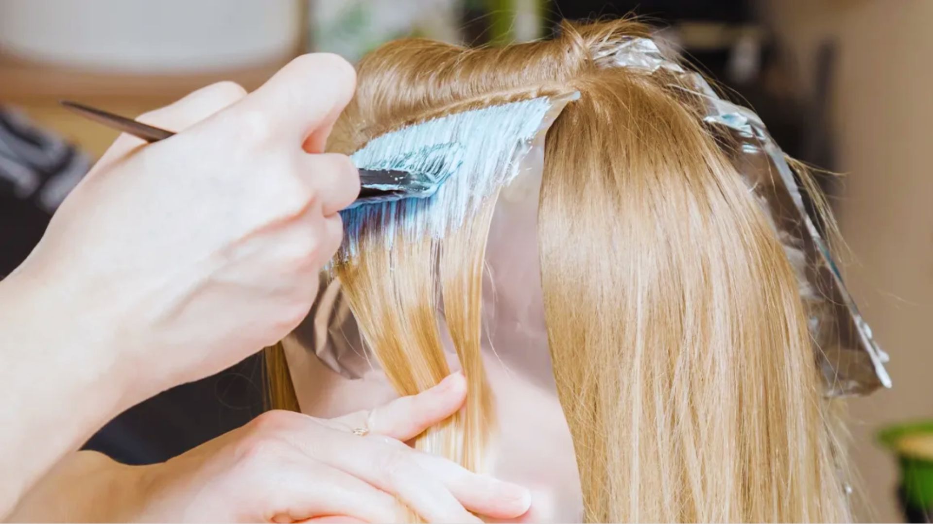A person is using a brush to cut a woman's hair in a salon setting.