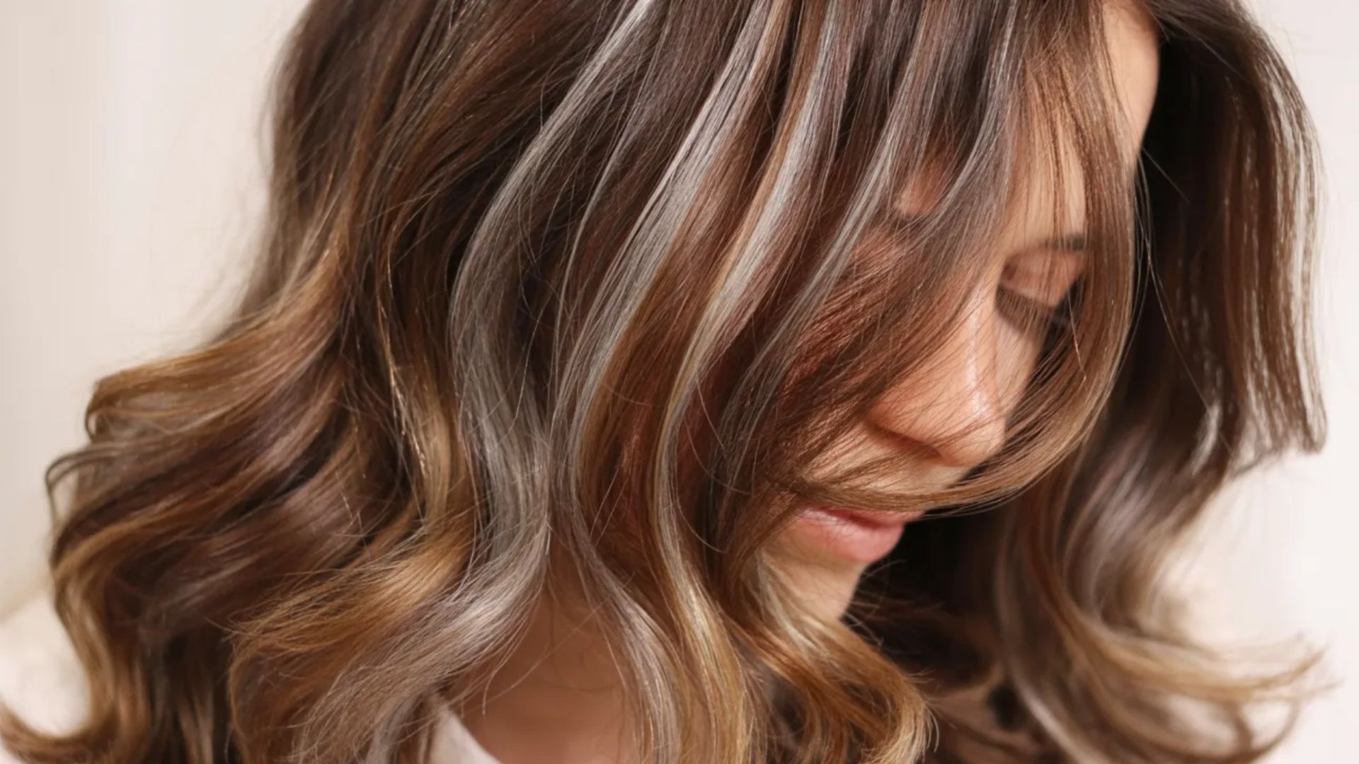 A woman with long, wavy hair is smiling, showcasing her hair's texture and movement.