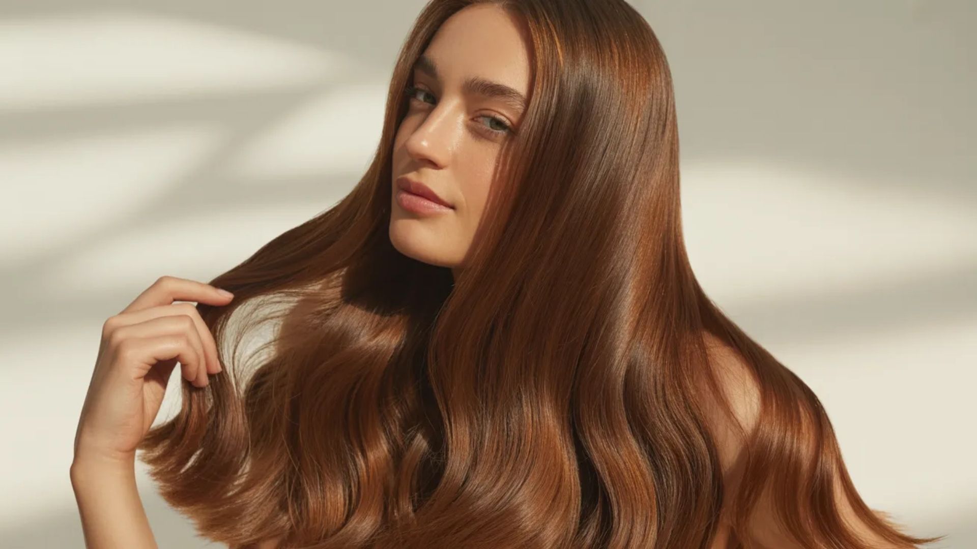 A woman with long, straight hair stands confidently, showcasing her hairstyle against a neutral background.