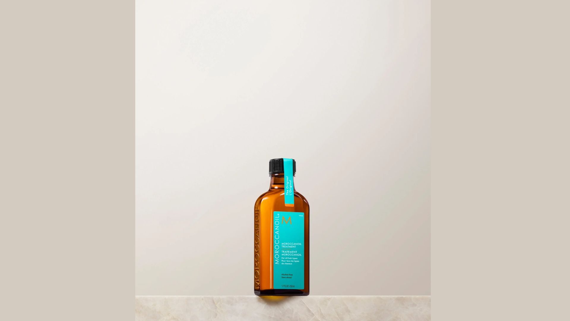 A glass bottle of olive oil rests on a smooth marble countertop, reflecting light and highlighting its vibrant color.