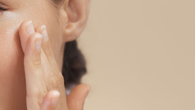 A woman with her hands on her face, indicating a moment of reflection or emotional response.