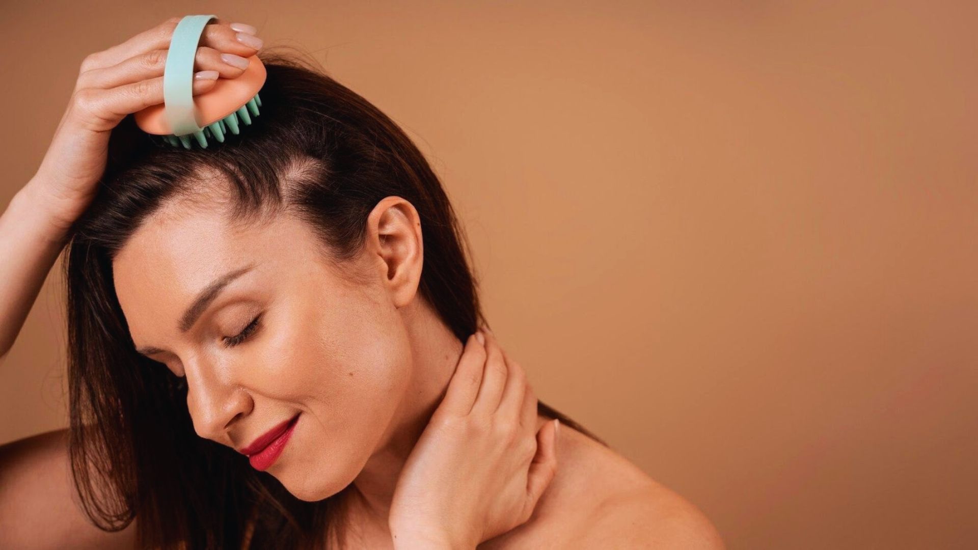 A woman uses a hairbrush to style her hair, looking content as she works through her locks.