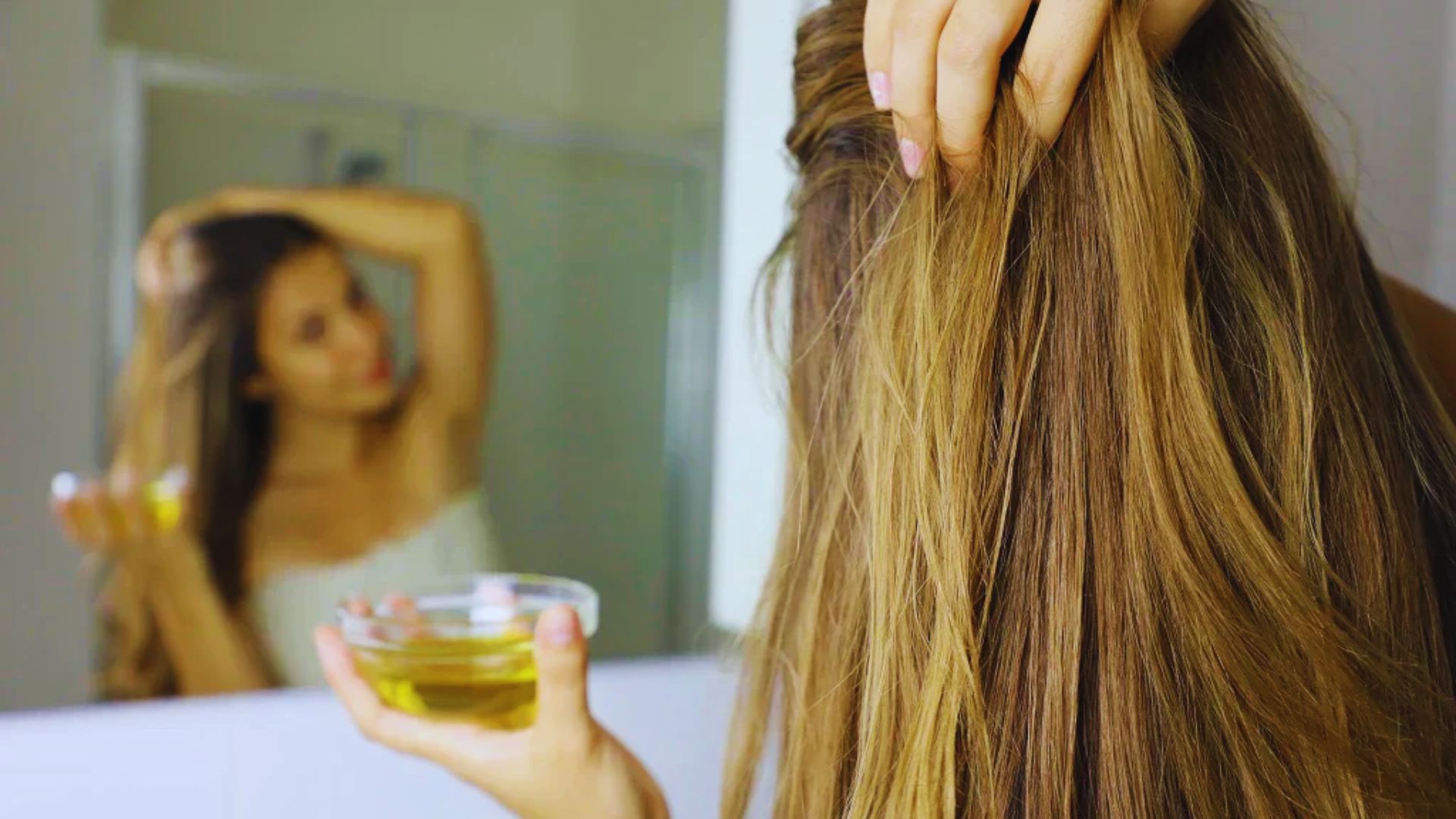 A woman combs her hair while holding a glass of water in her other hand.