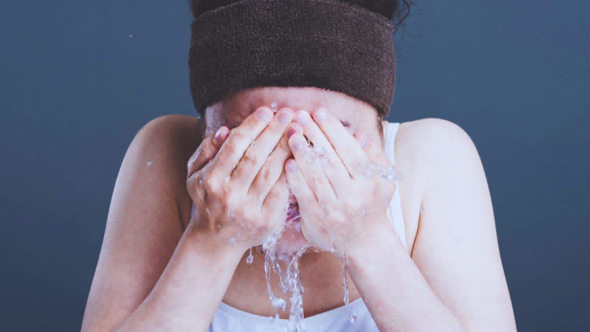 A woman with water dripping from her face, illustrating the effects of cold water on skin pores.