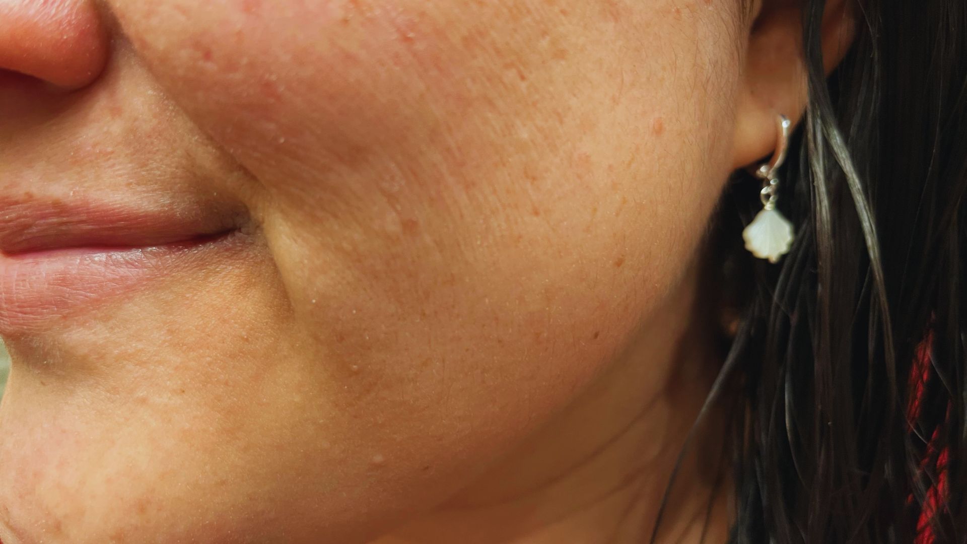 Close-up of a woman's face showcasing her earrings, highlighting her features and jewelry.