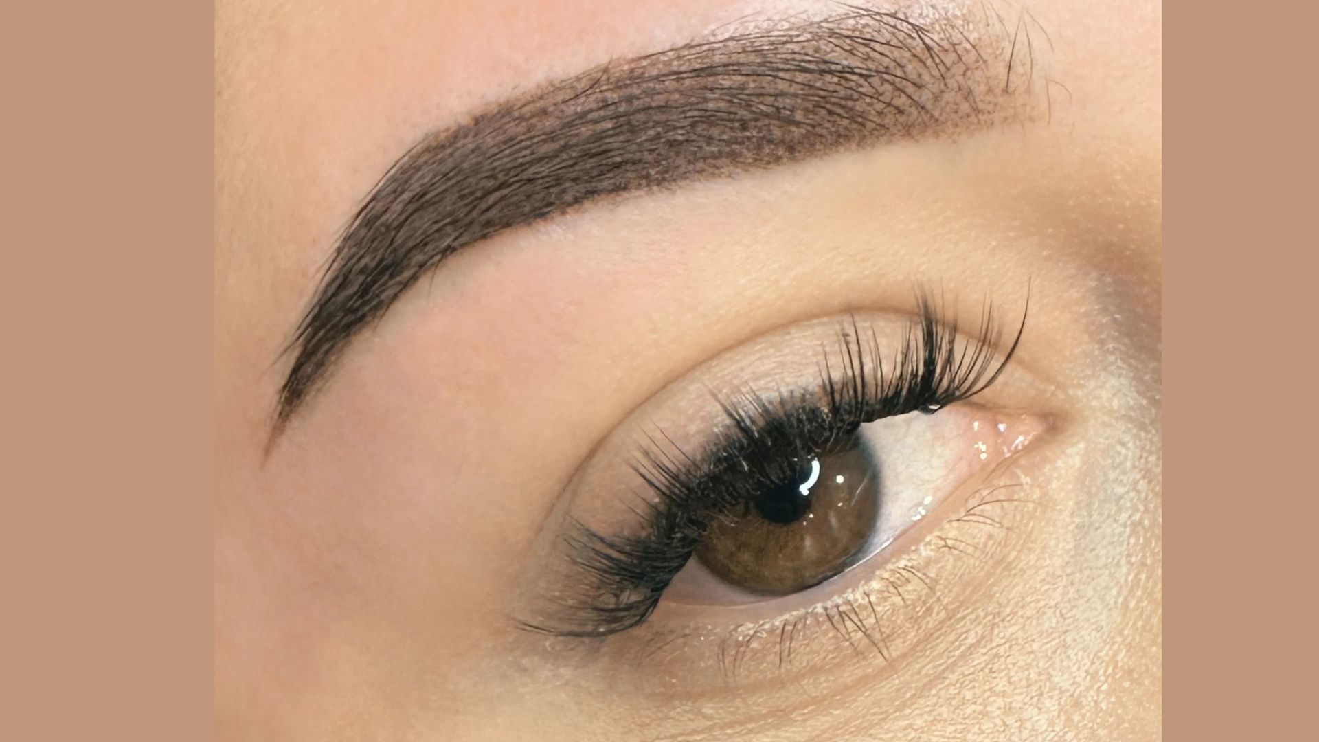 A close-up of a woman's eye featuring long eyelashes and well-defined brown eyebrows.