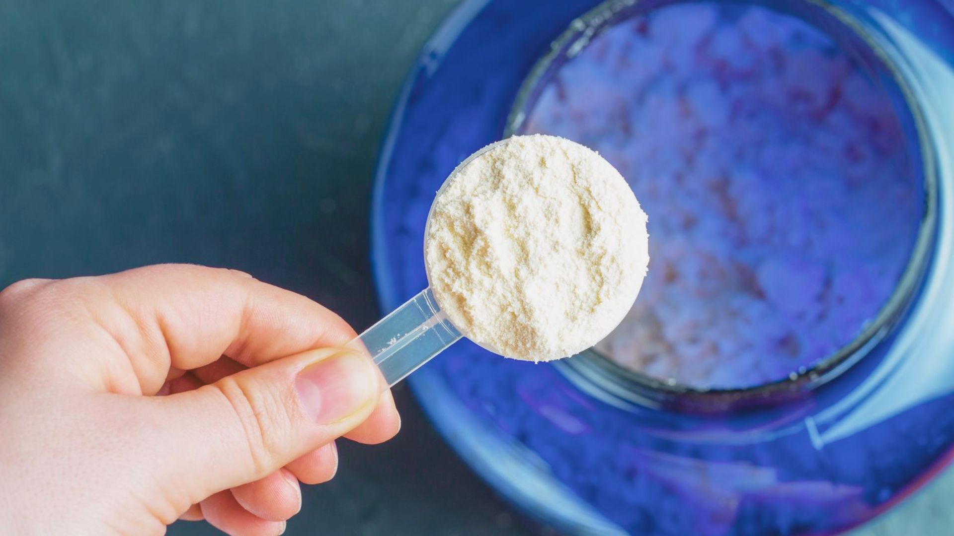 A hand with a spoon hovers over a bowl of powder, suggesting a discussion on whether creatine contributes to acne.