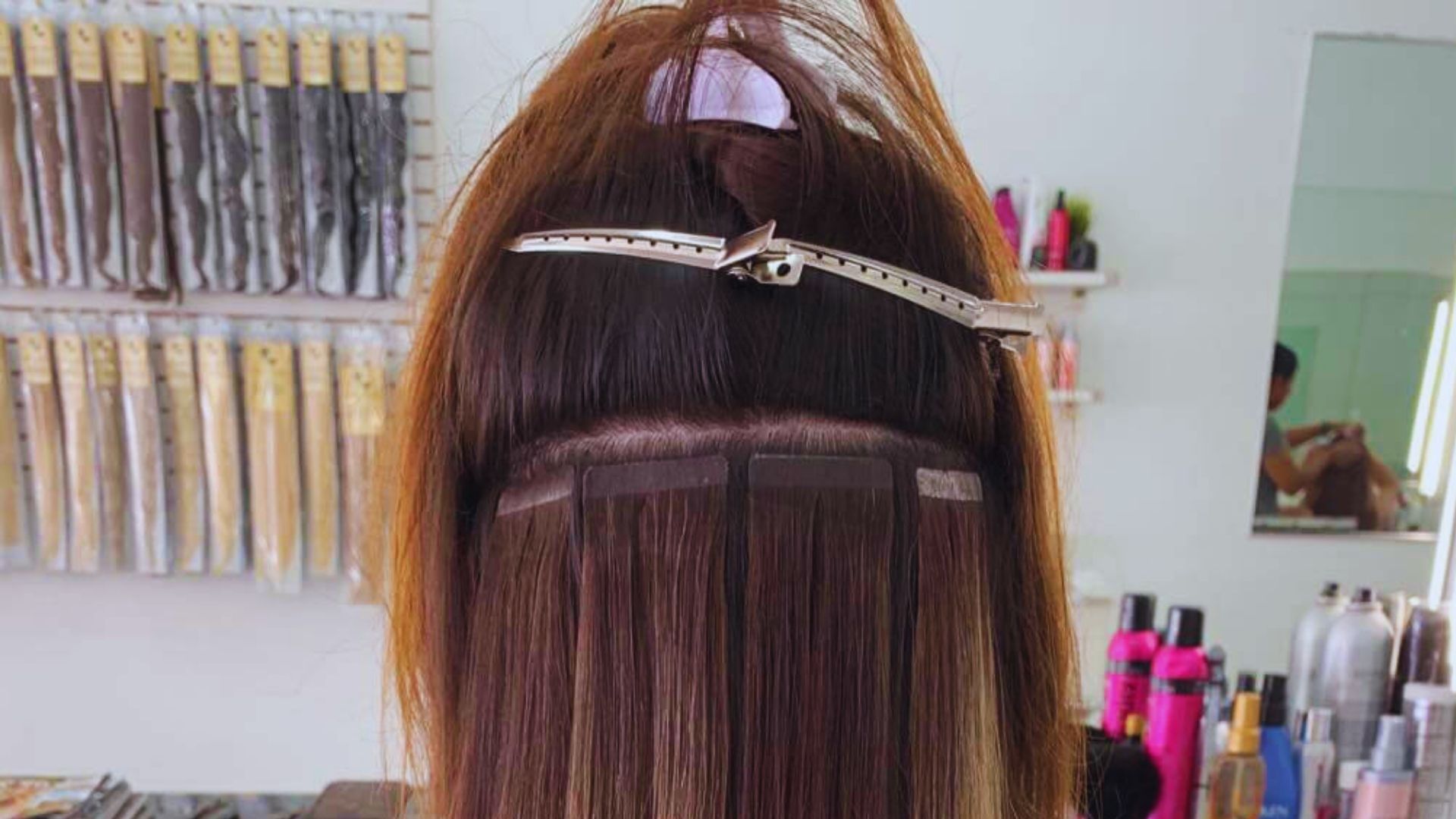 A woman with dark brown hair styled with clip-in hair extensions, showcasing a voluminous and trendy look.