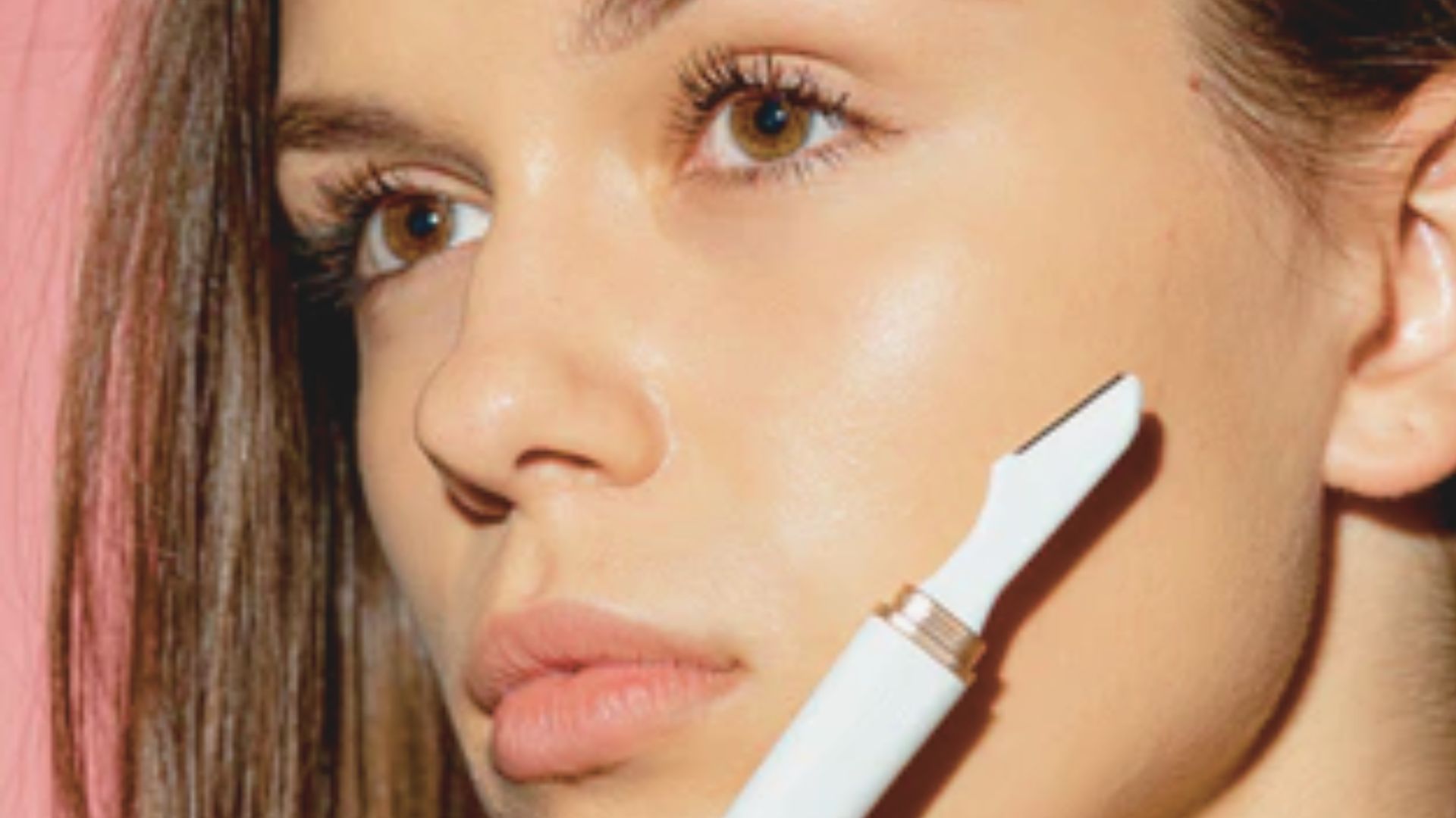 A woman gently brushes her face, focusing on cleansing her skin with a soft facial brush.