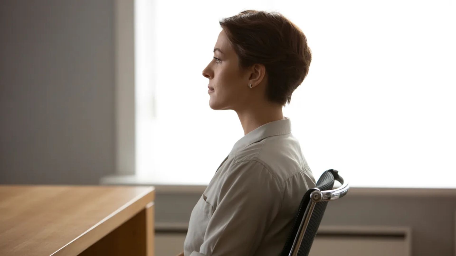 5. A woman seated at a desk in an office, focused on her work with a computer and documents around her.