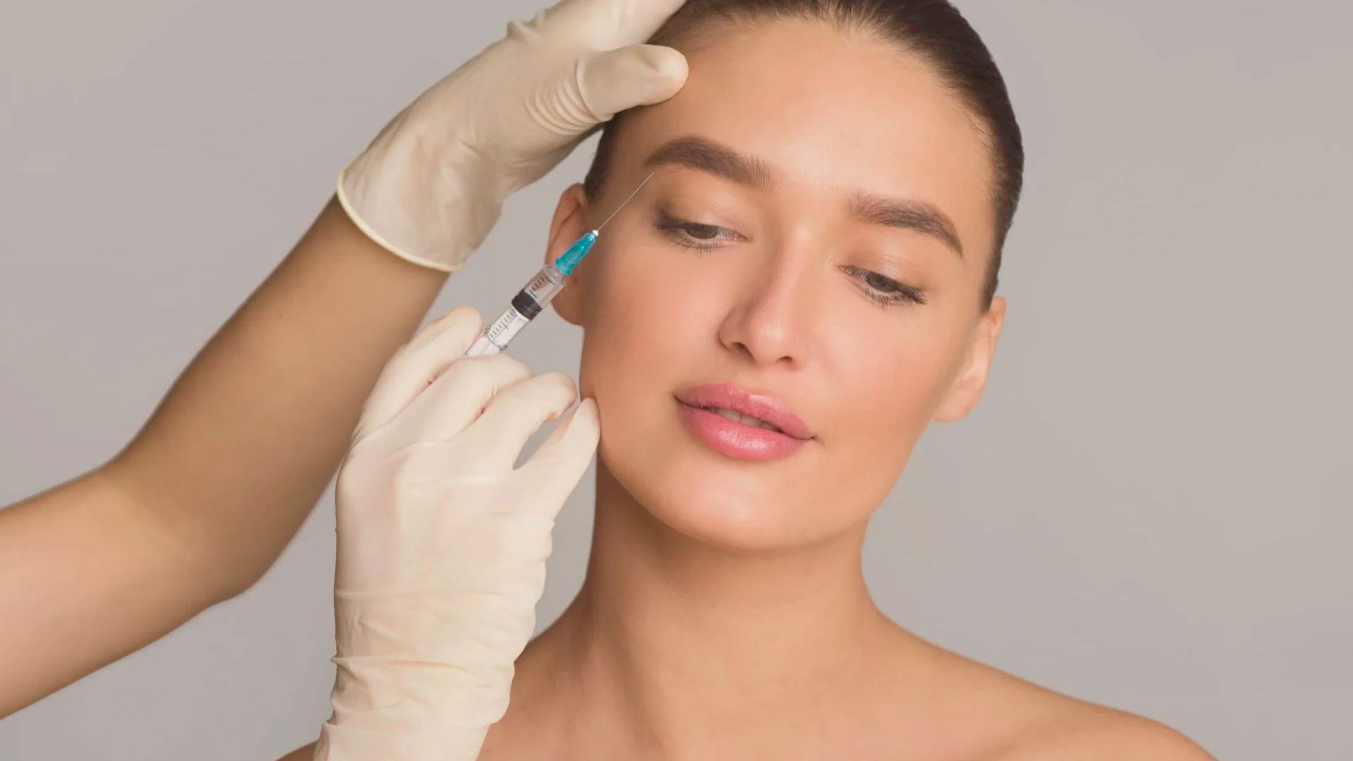 A woman receiving an injection in her face, with a healthcare professional administering the procedure.