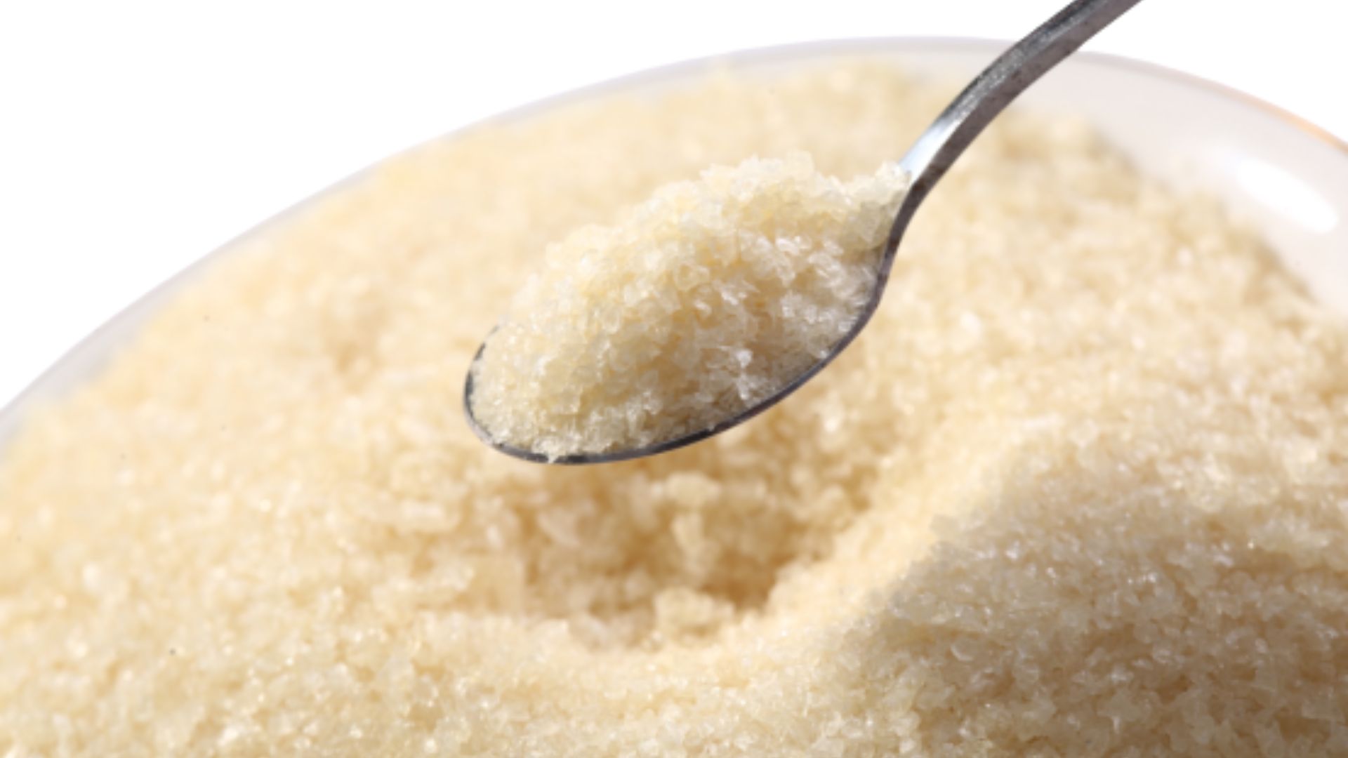 A spoonful of sugar resting in a small bowl, showcasing the granulated texture and white color of the sugar.
