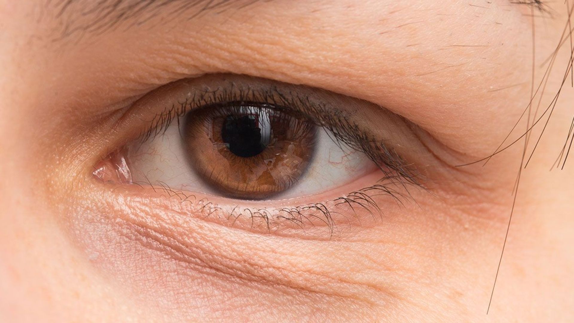 Close-up of a woman's eye, showcasing her brown skin and intricate details of the iris and eyelashes.