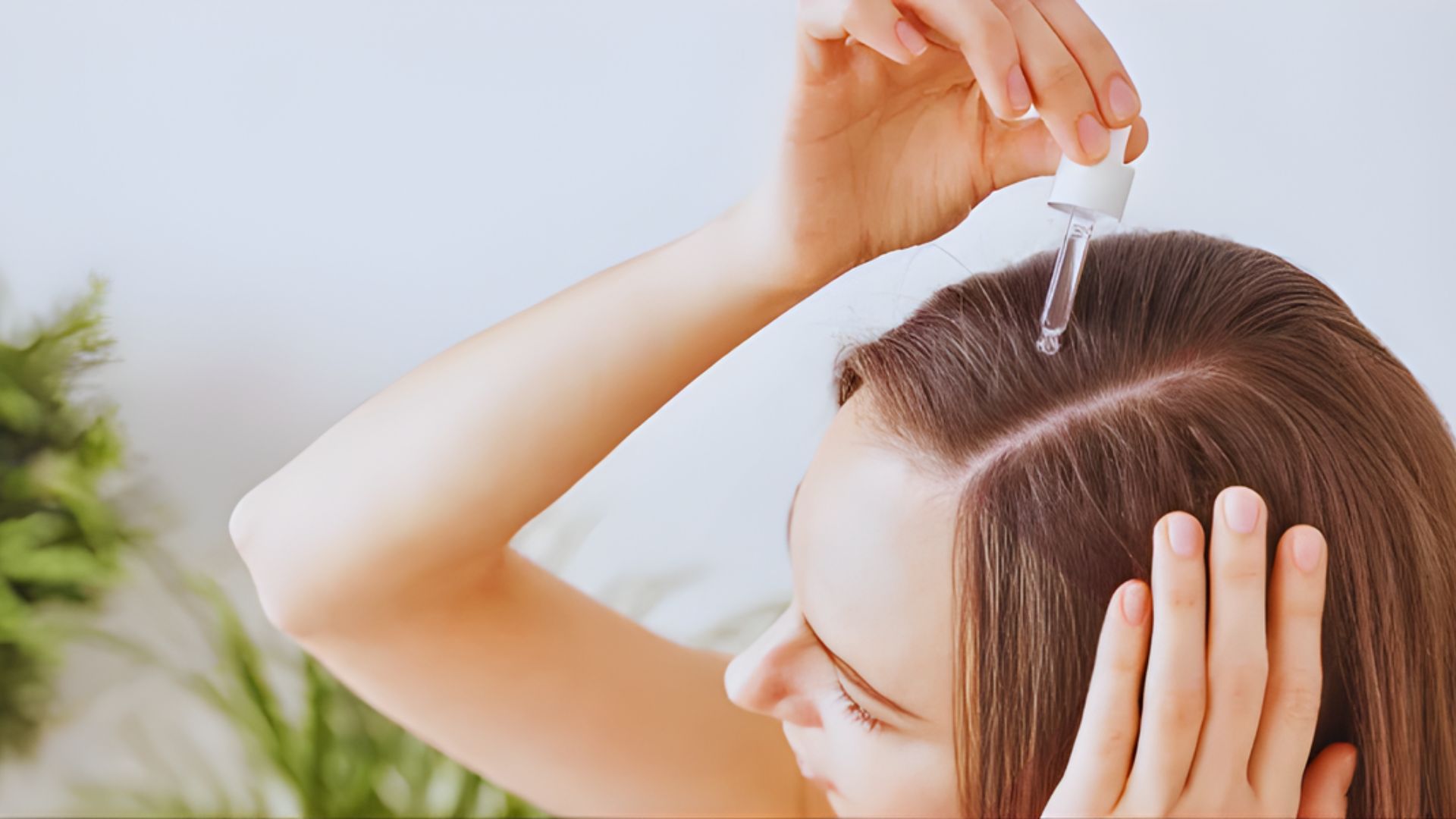 A woman applying castor oil to her hair, focusing on nourishing and moisturizing her strands.