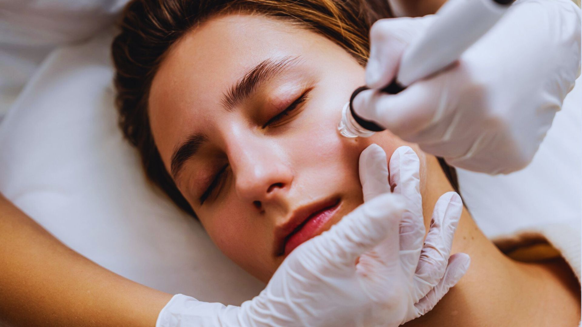 VAA woman applies a liquid treatment to her skin, comparing Hydrafacial and Diamond Glow skincare methods.