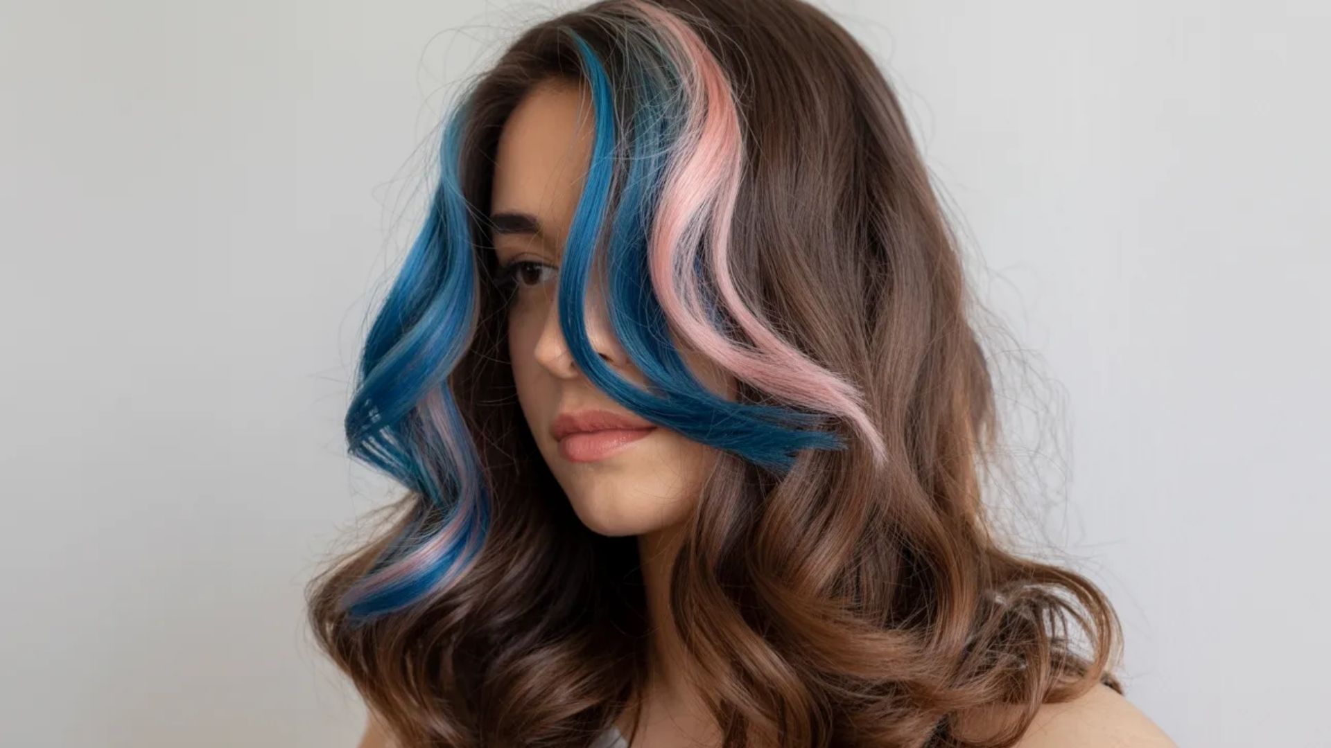 A woman showcasing her unique blue and pink hair, styled elegantly, with a cheerful expression.