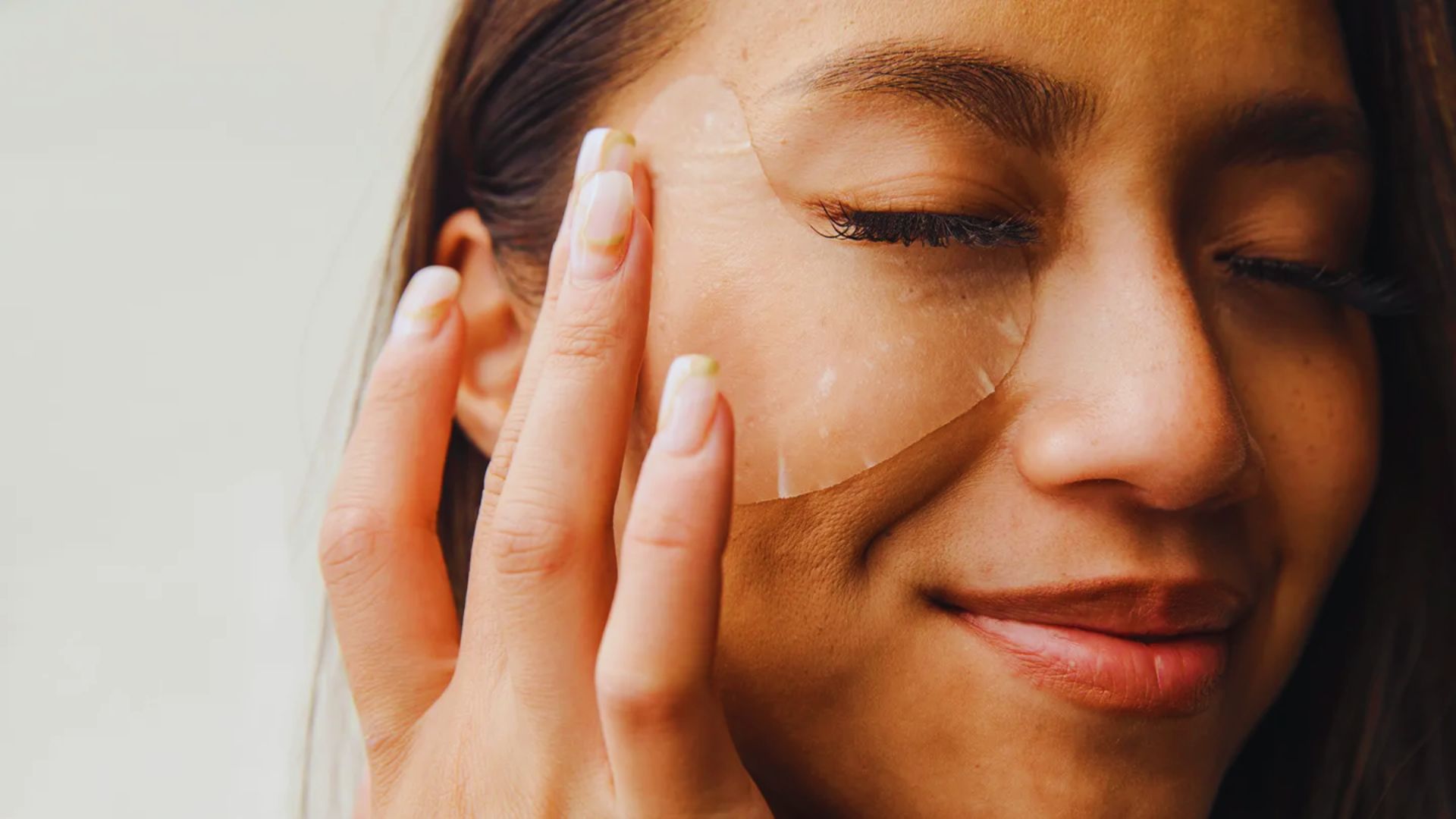 A woman with a pale complexion wearing a white eye patch, gazing thoughtfully into the distance.