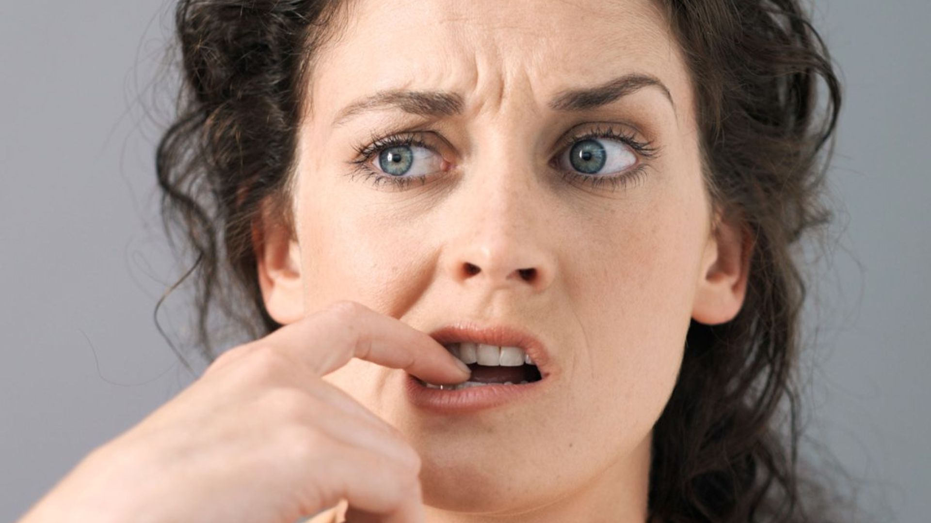 A woman holding a toothbrush, preparing to brush her teeth.