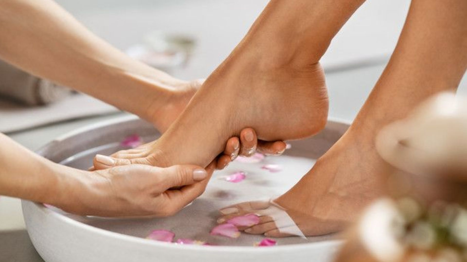 A woman relaxes as her feet are gently washed in a bowl of water.