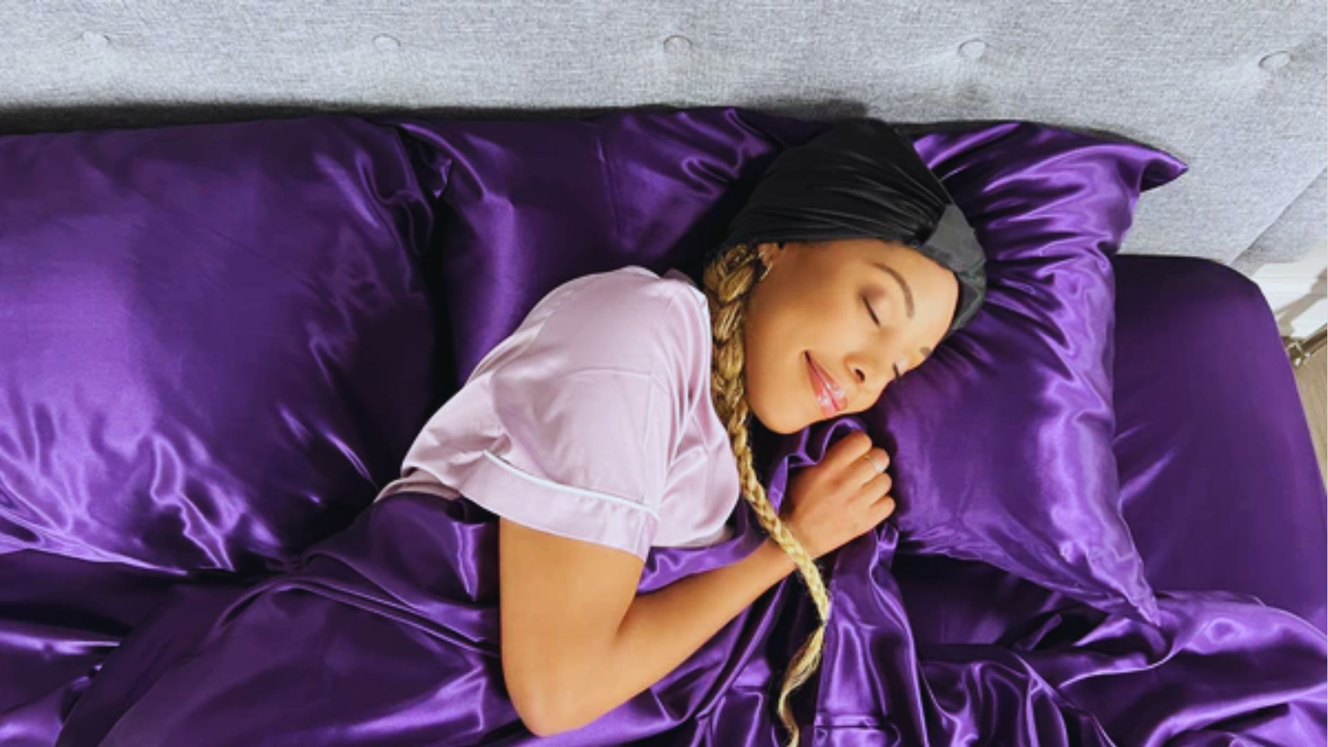 A woman peacefully sleeping on a purple bed, resting her head on a soft pillow.