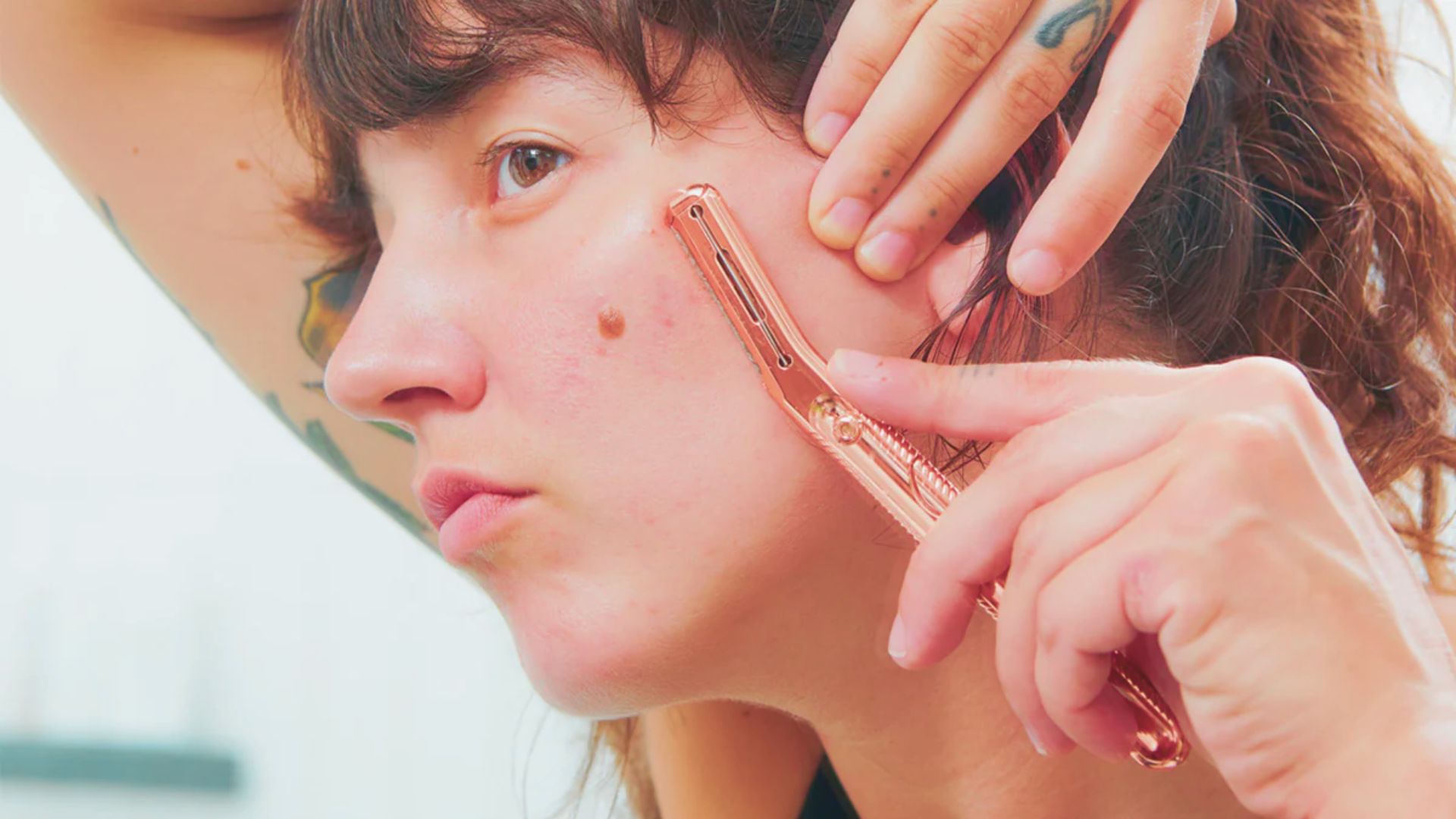 A woman with tattoos is using a comb to brush her hair, showcasing her unique style and personal expression.