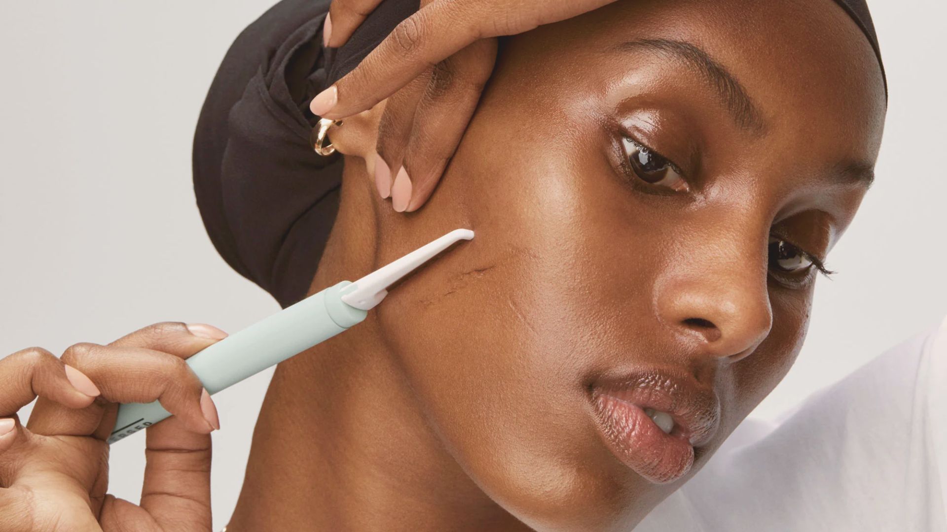 A woman receives a skin treatment as a professional uses a brush on her face.