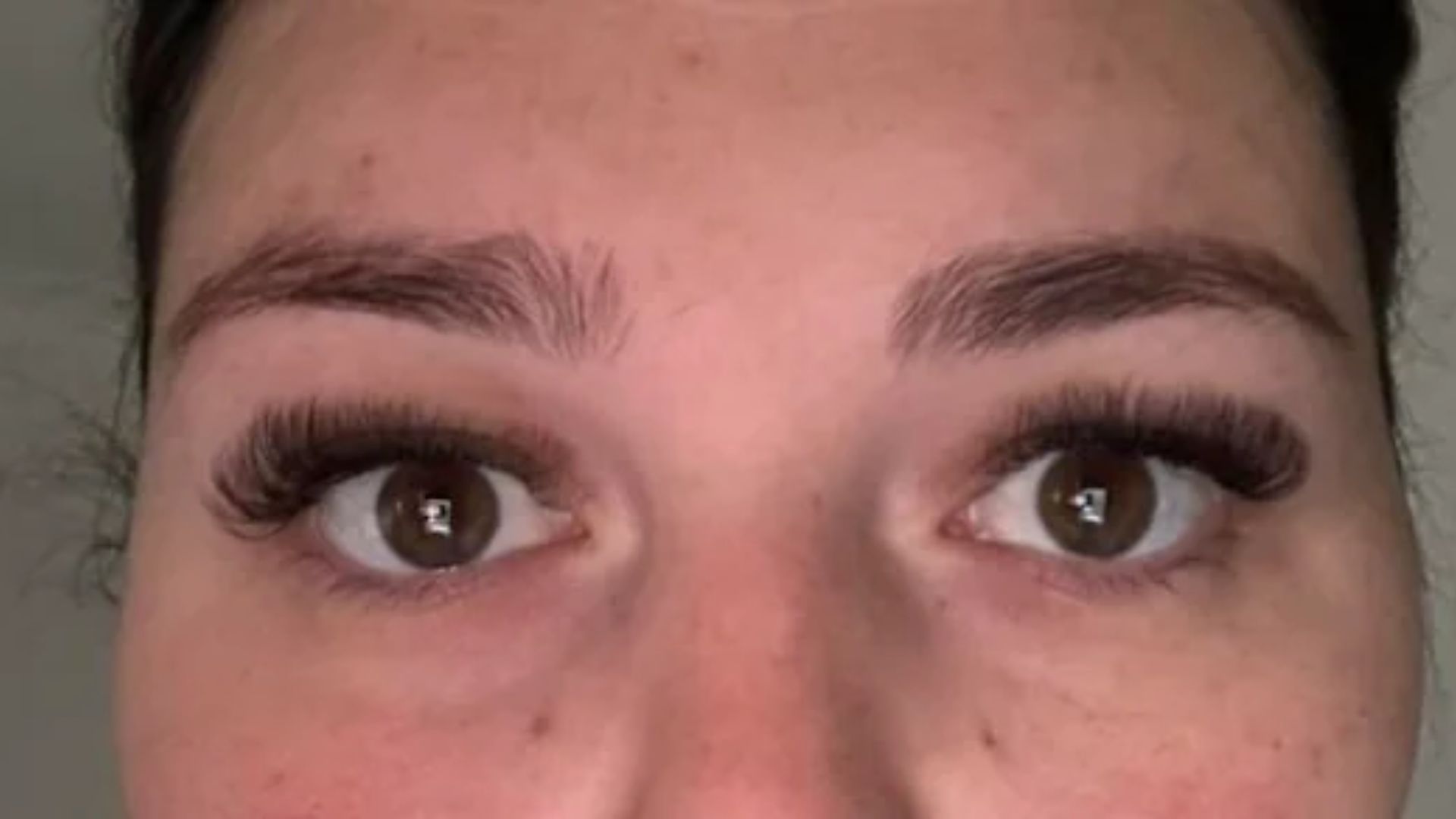 A woman with long eyelashes and a bright smile, radiating joy and warmth.