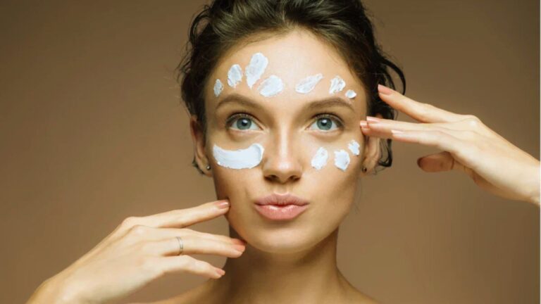 A woman applying cream to her face, showcasing a skincare routine.