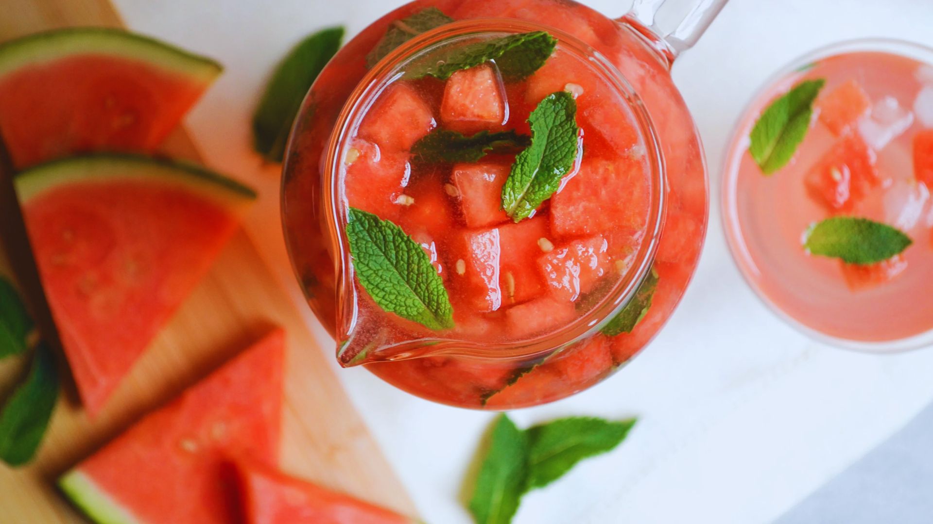 A vibrant display of sliced watermelon with fresh mint leaves scattered throughout, emphasizing a refreshing summer treat.