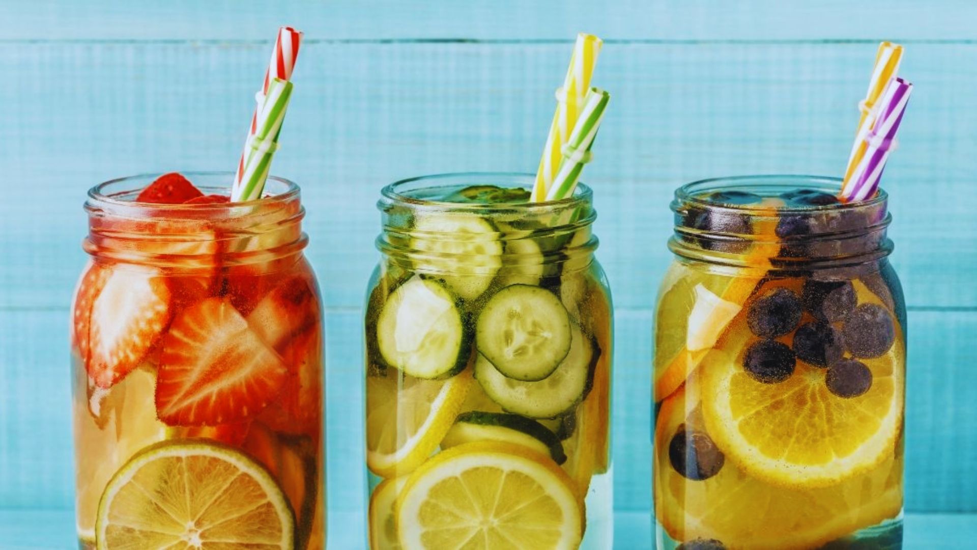 Three jars filled with colorful fruit and vegetables arranged on a wooden surface.